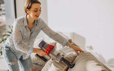 Young woman with rechargeable vacuum cleaner cleaning at home